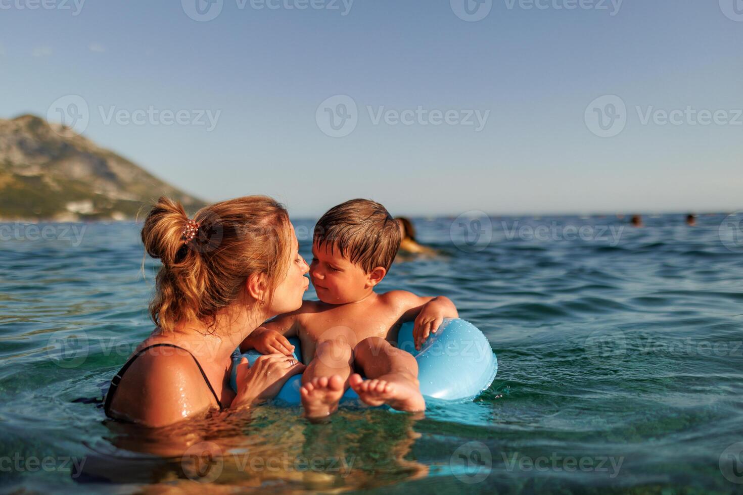 Caring mother rides her son on an inflatable ring in the seaMother rides son on inflatable ring in seaMother rides son on inflatable ring sea photo