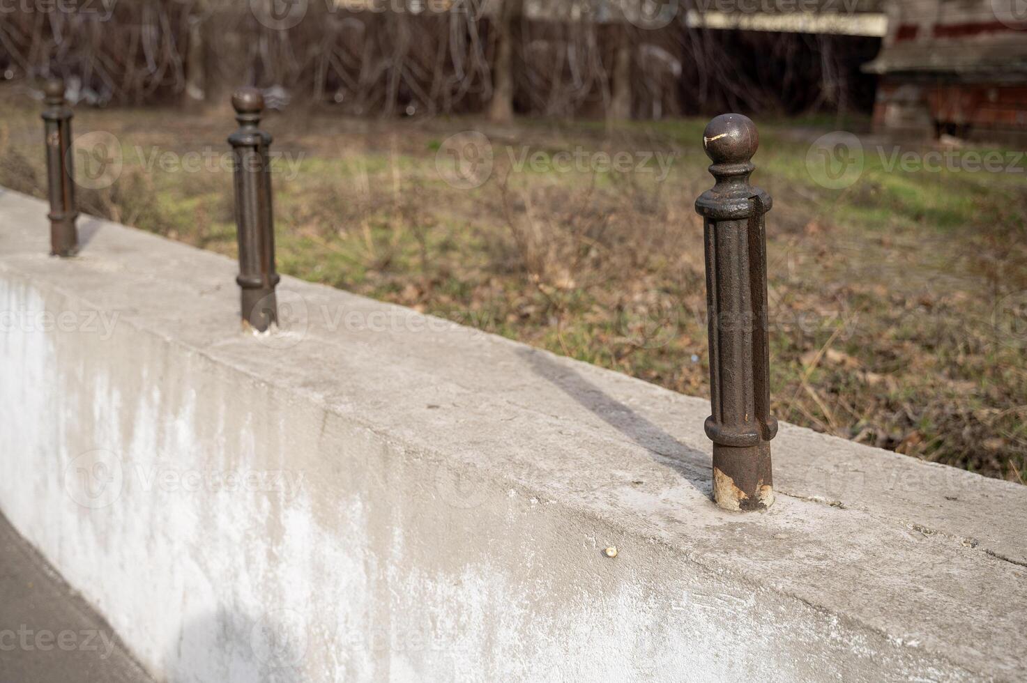 Cast iron posts in a row, on a concrete base, on the street, in a park photo
