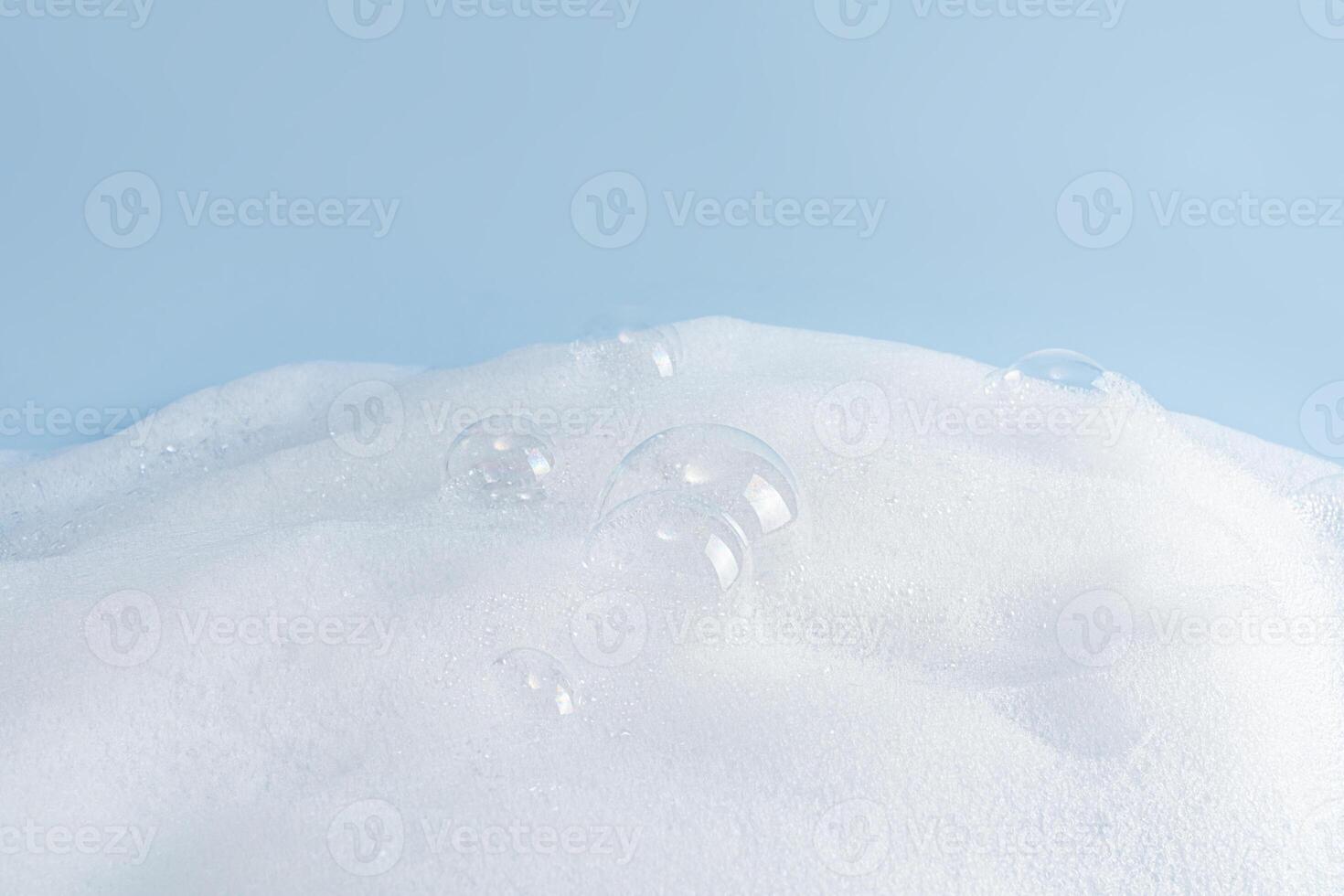 Chic white fluffy foam, soap foam texture with clear bubbles on blue background. A copy space. Layout for advertising detergent, spa cosmetics. photo