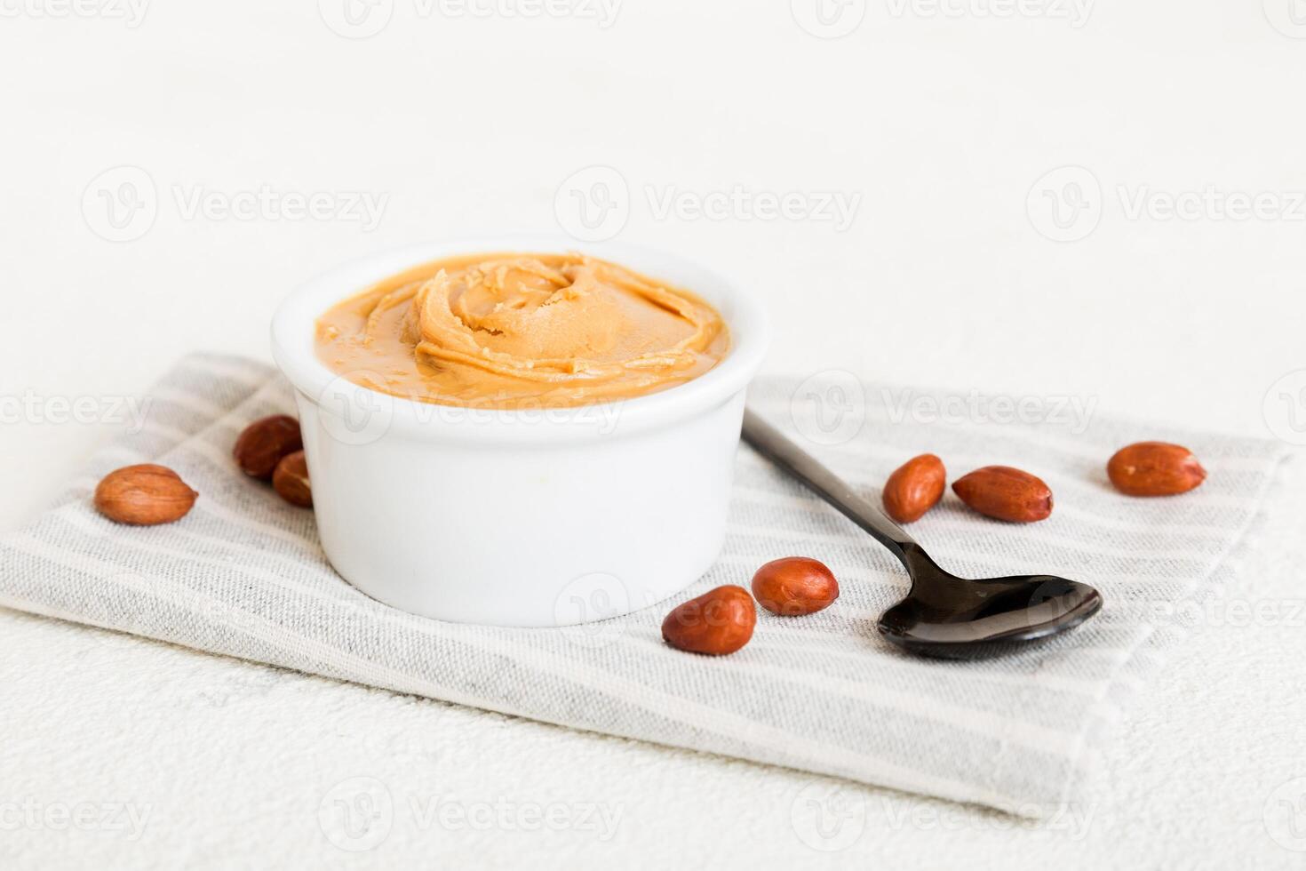 Bowl of peanut butter and peanuts on table background. Creamy peanut pasta photo