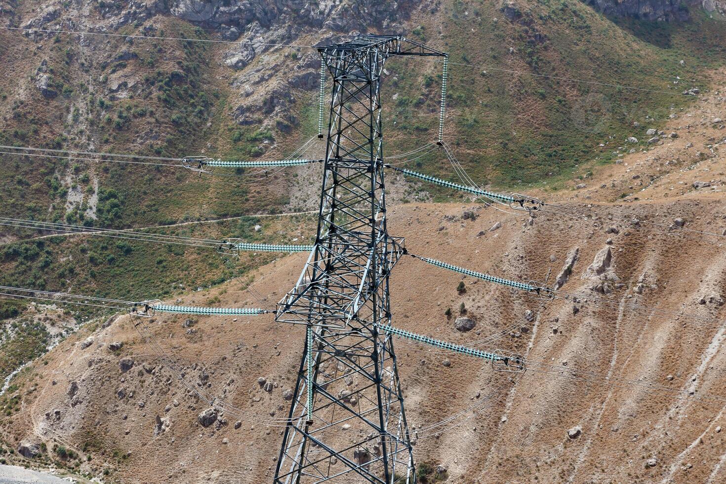 Electricity transmission tower stands amidst rugged terrain in Tajikistan photo