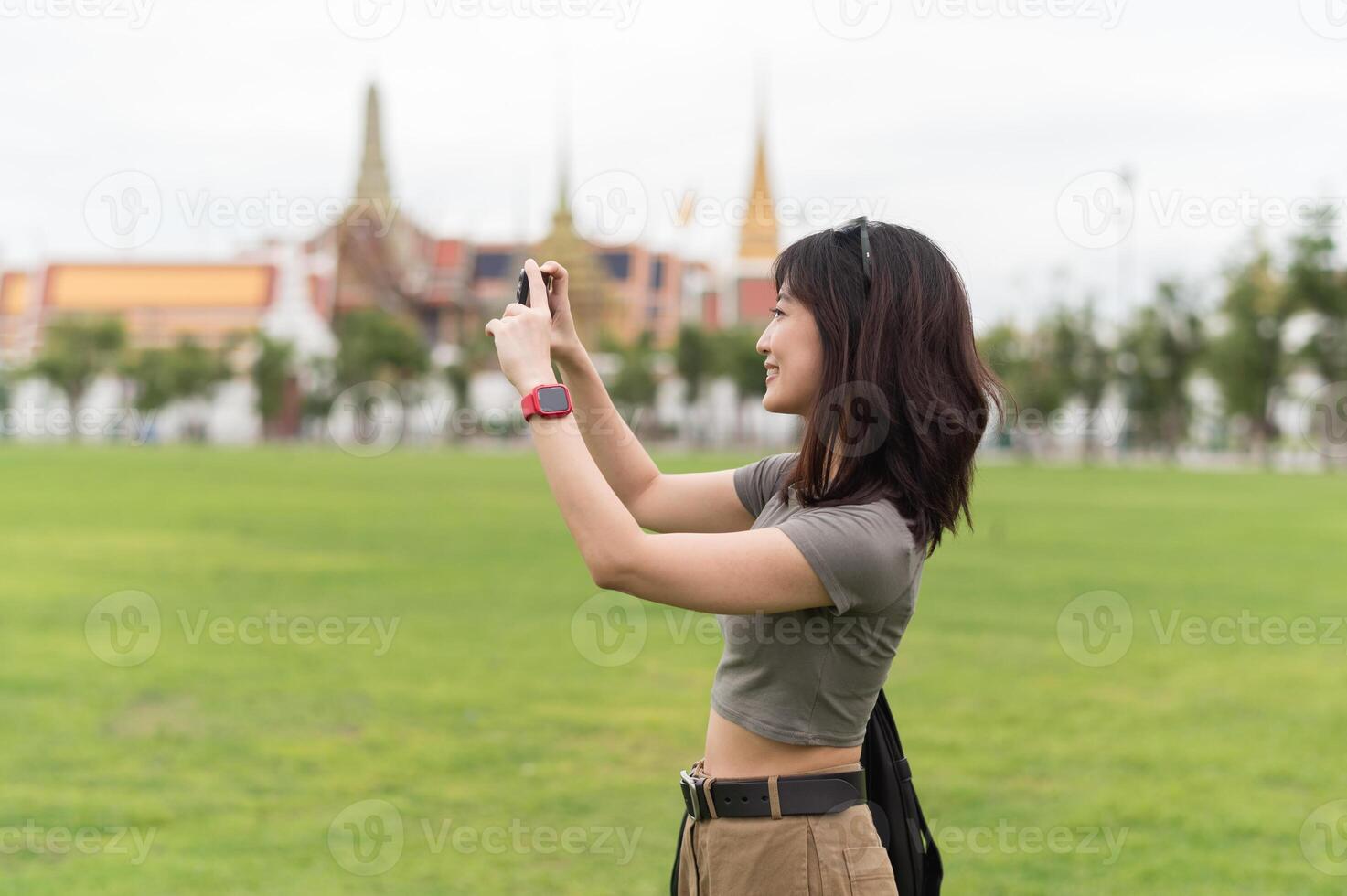 Happy southeast asian woman teenager blogger world explorer on solo travel. Take photo with smartphone. local cultural tourism experience concept in Bangkok, Thailand, Asia