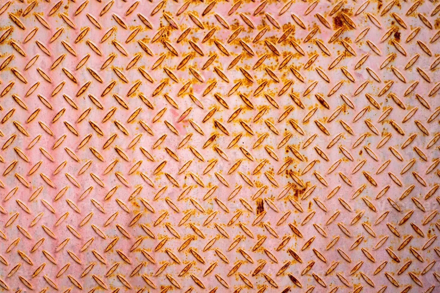 Close up of rusty diamond plate metal with a pinkish tone. Industrial texture background ideal for design, construction, or engineering concepts. High detail and symmetrical pattern. photo
