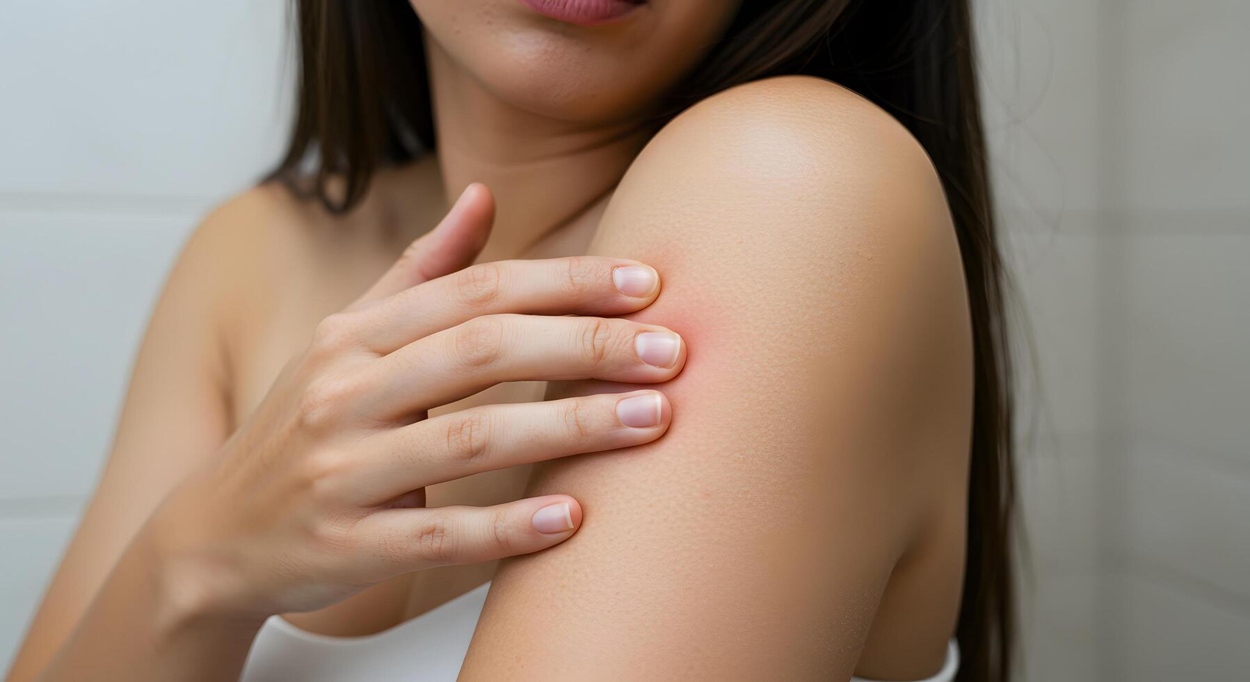Close-up of woman pressing a red boil on her shoulder, perfect for dermatology resources, acne awareness, or skin care blogs. photo