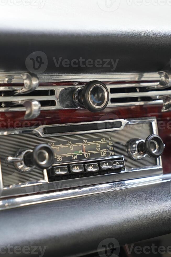 The dashboard of a vintage classic car features detailed analog gauges, a radio, and air vents in polished wood and chrome, offering a fresh yet luxurious look.eb photo