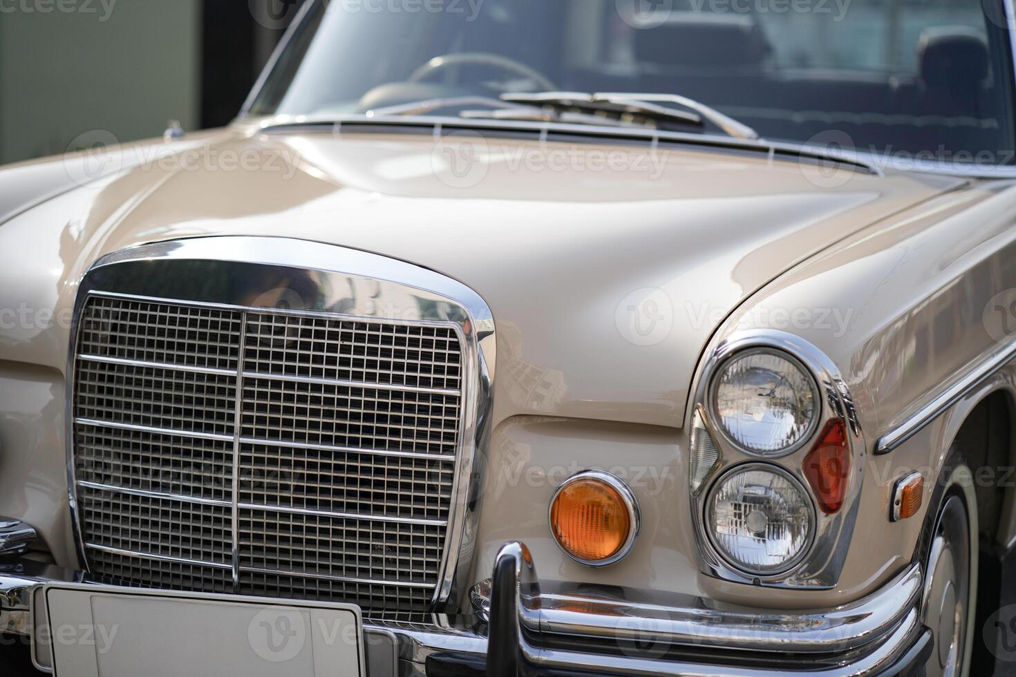 The round headlights and side turn signals on classic cars, framed in polished chrome, highlight the vintage style with old-fashioned lighting and curved fender details.bg photo