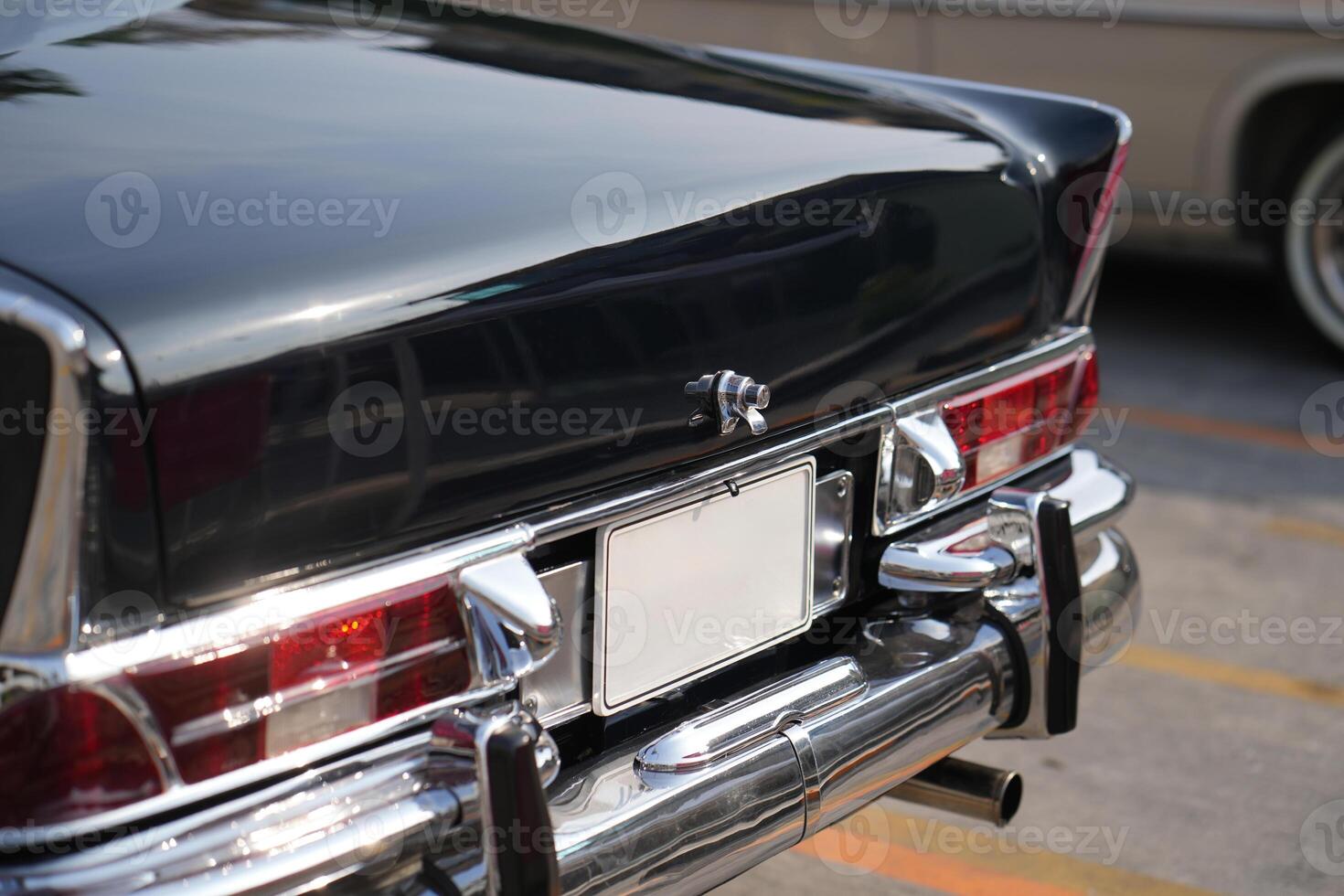 A chrome keyhole above the license plate and a polished rear trunk lock system on a vintage car highlight its sturdy and secure mechanical design.h photo