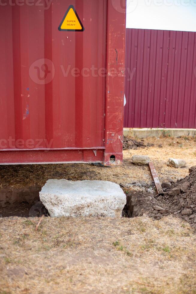 A cargo container rests partially on a concrete foundation, Installing the container in place photo