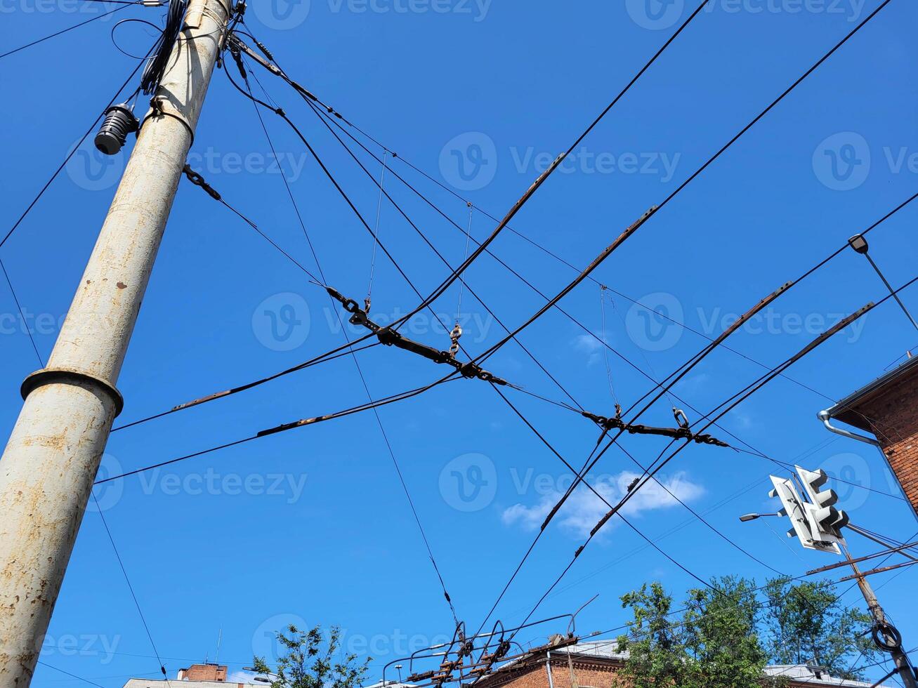 A pole with trolley wires against a blue sky. Electric power cables against a blue sky. Transmission line cables. photo