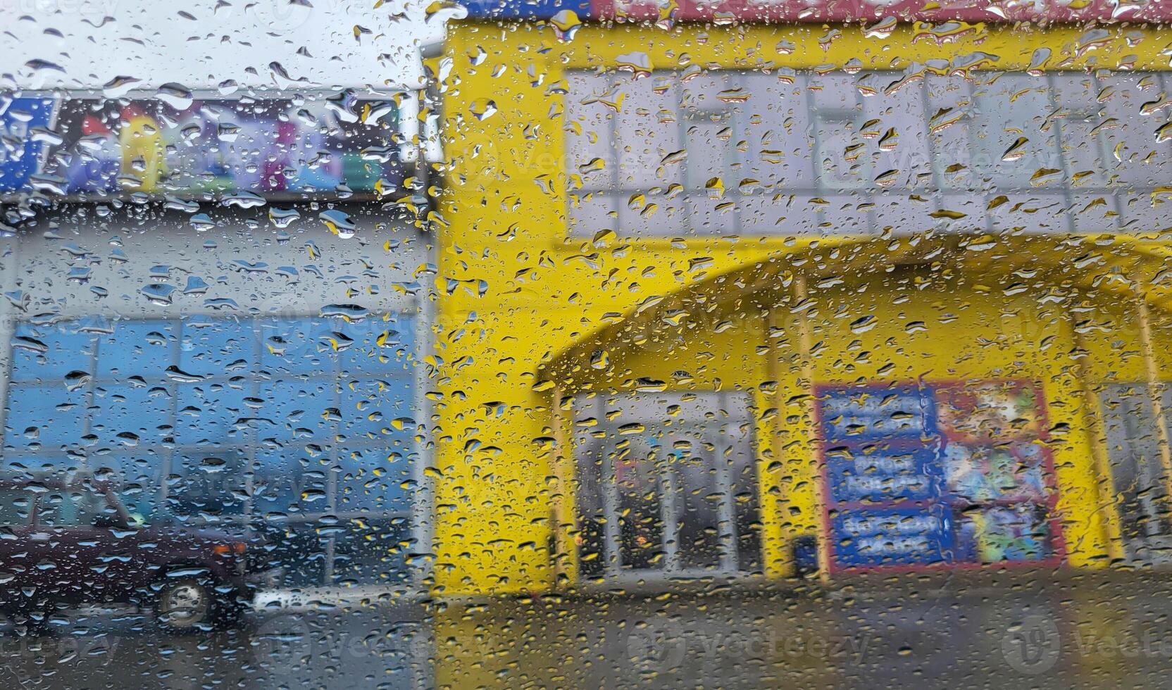 Transparent raindrops on the window. View through a rain-soaked window at a blurred background with houses. photo