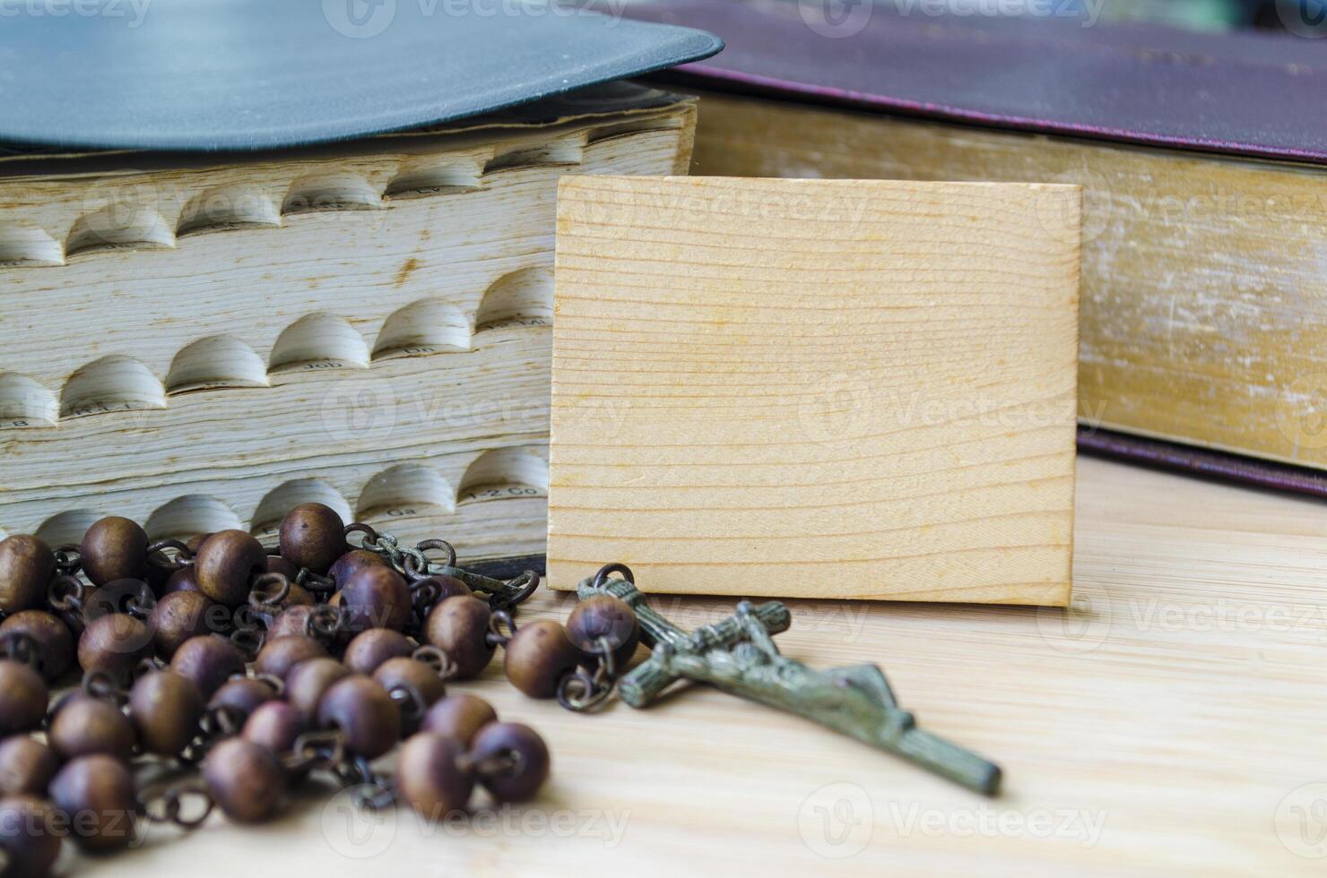 Holy Bible and Holy Rosary placed beside wooden block with customizable space for text or message sharing. Religion and Christianity concept photo