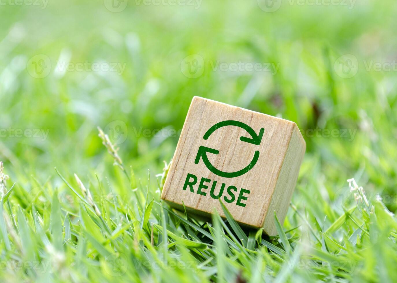 Wooden cube showing reuse symbol on grassy background photo