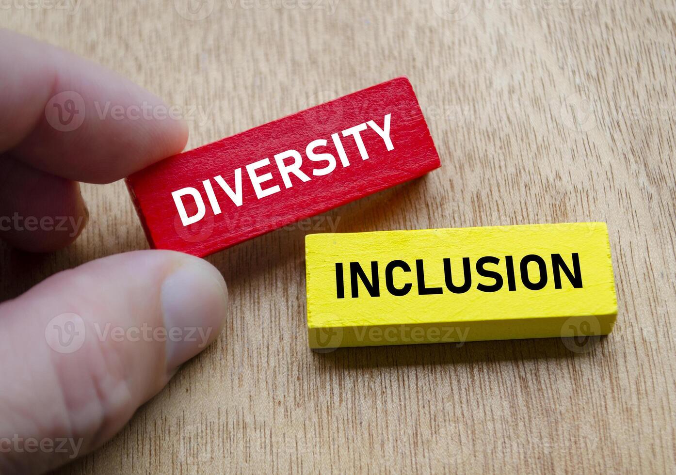 Diversity and Inclusion shown by hand holding red and yellow wooden blocks. Diversity and inclusion concept. photo