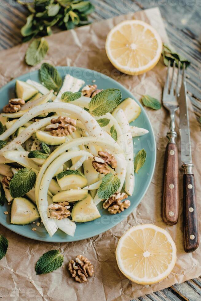 Healthy eating raw fennel salad with walnuts, raw courgettes, mint leaves and lemon juice photo