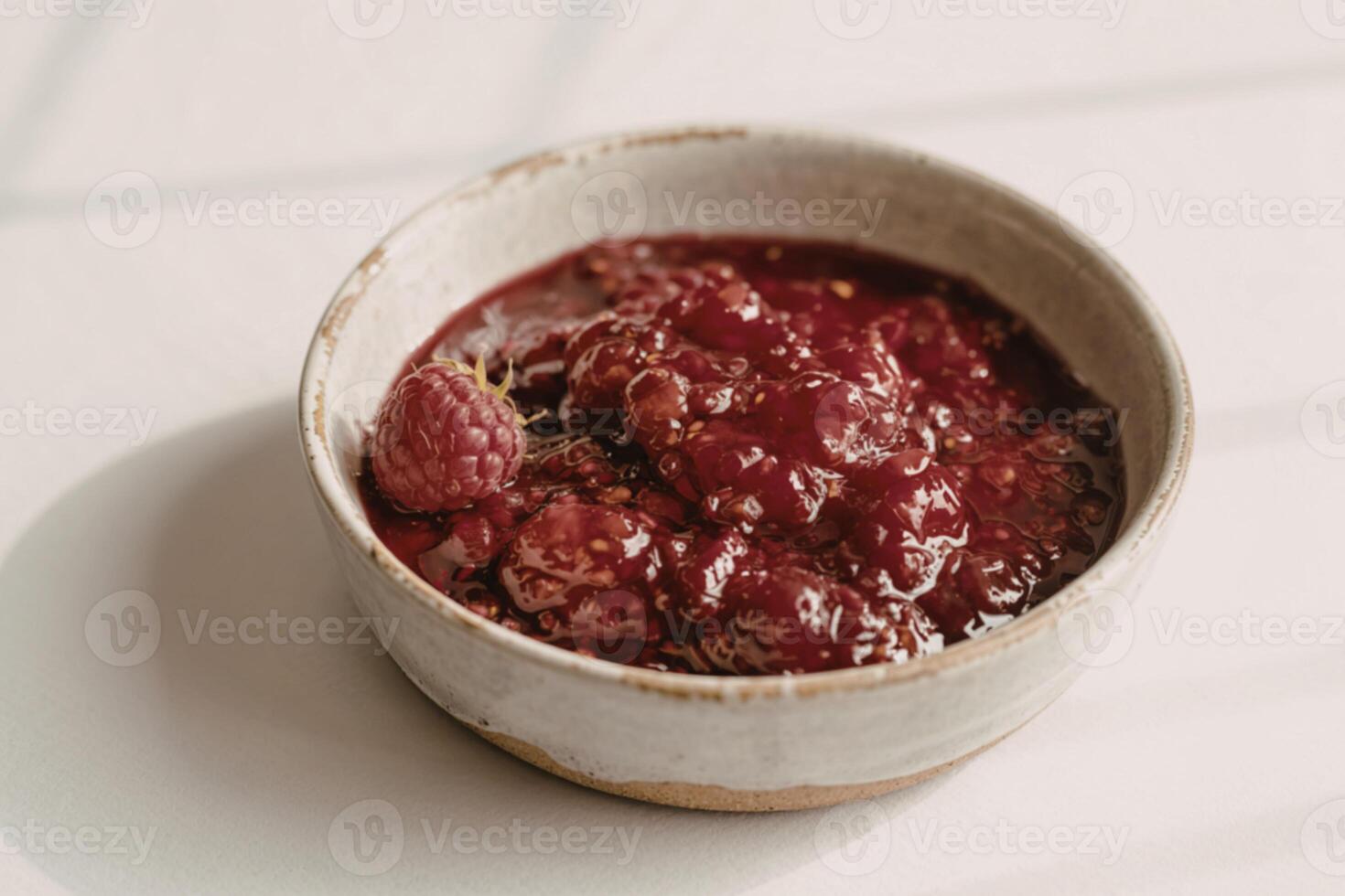 a ceramic bowl filled with glistening raspberry jam photo