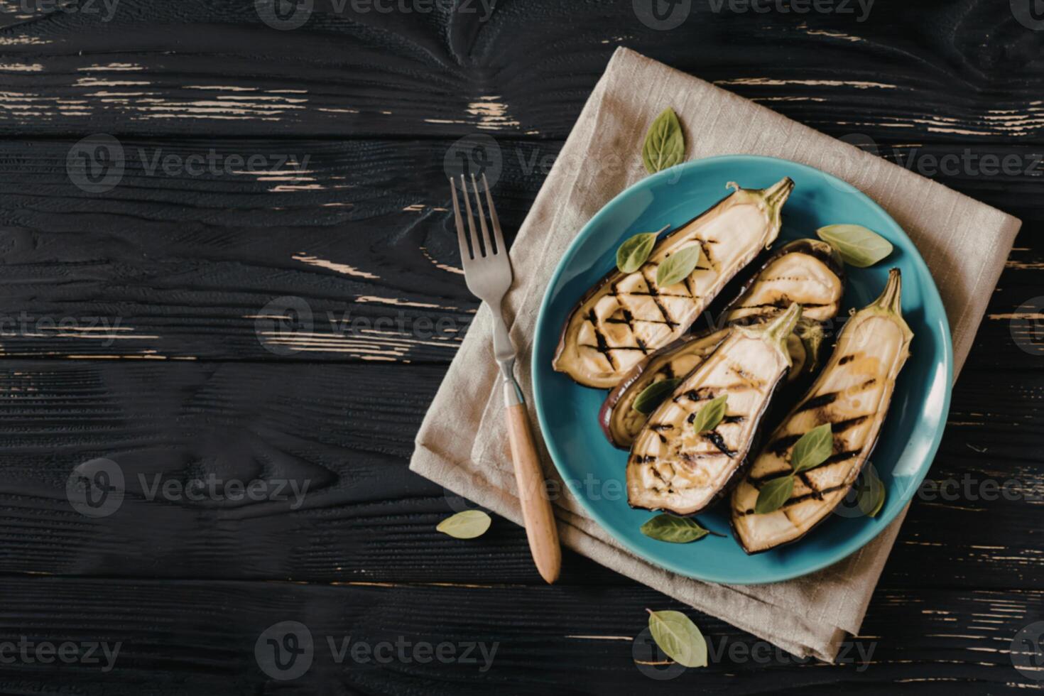 Grilled eggplants in plate has fork on isolated on black wood background photo