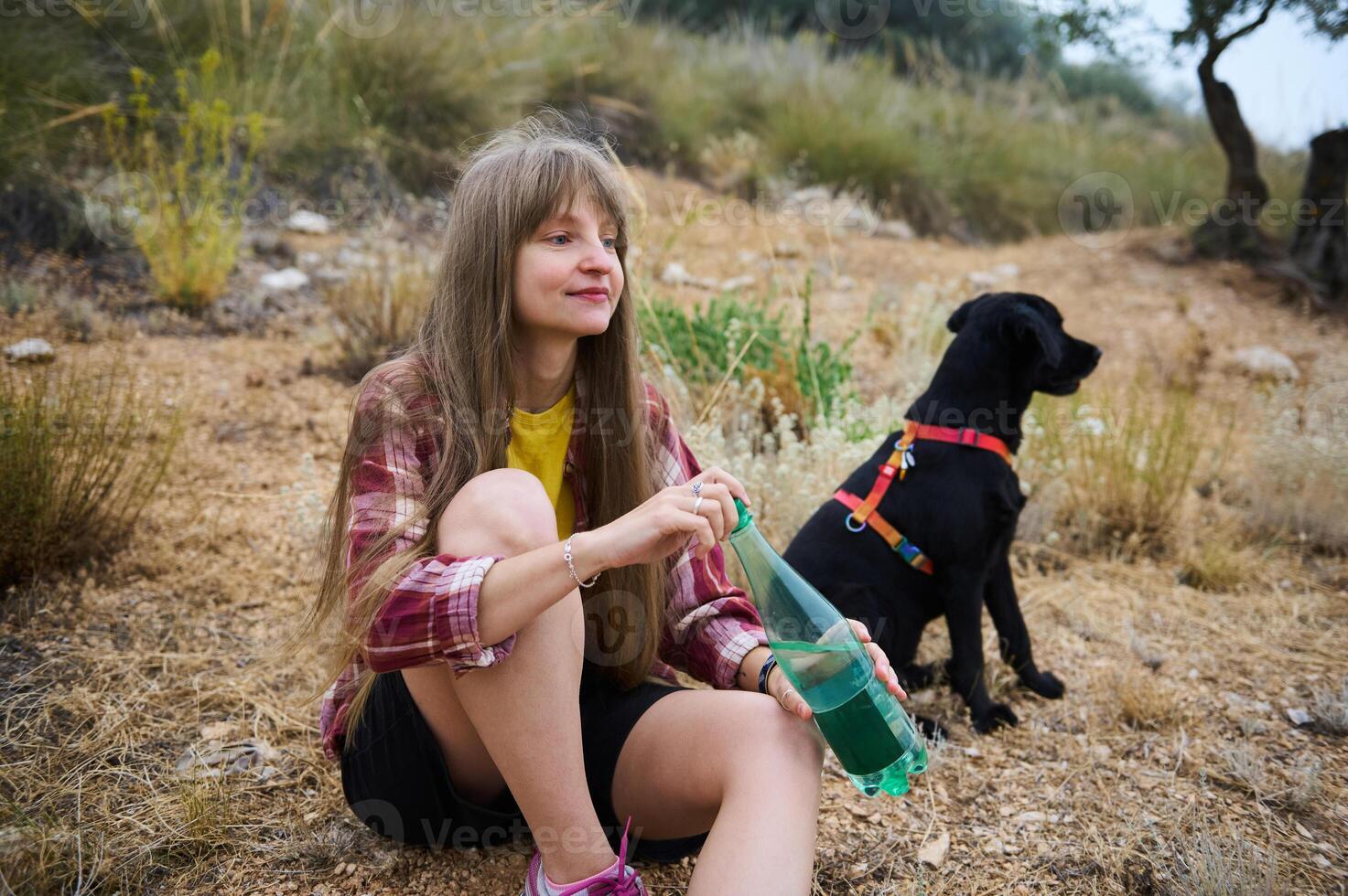 Young Woman Relaxing Outdoors with Her Dog, Embracing Nature photo