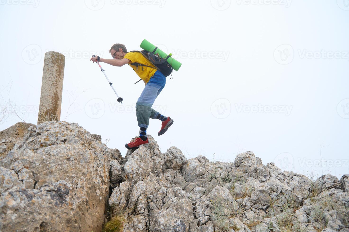 Adventurous Hiker Scaling Rocky Outcrop with Gear in Bright Daylight photo