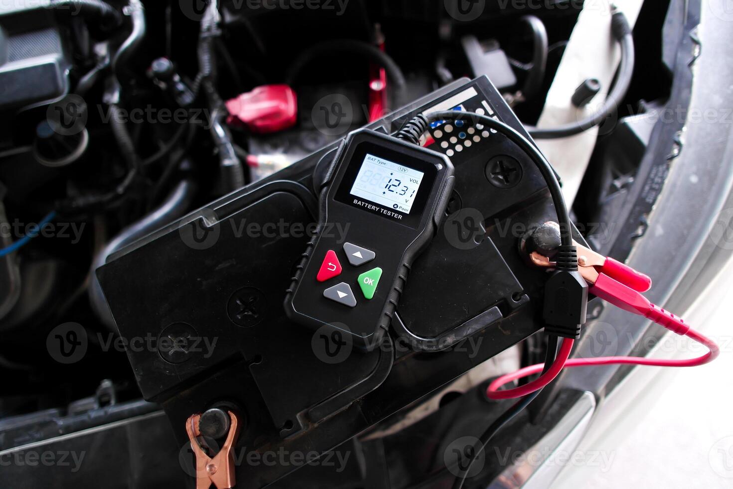Car battery being tested with a battery tester, vehicle maintenance with diagnostic tool. photo