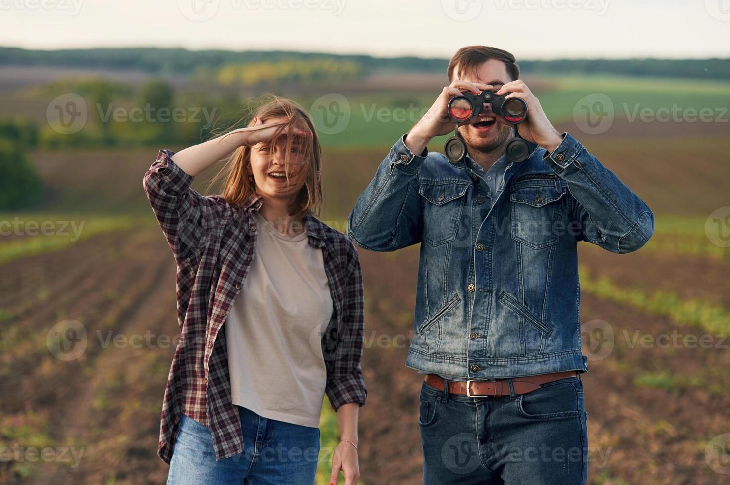 Using binoculars. Lovely beautiful couple, are together on the agricultural field photo
