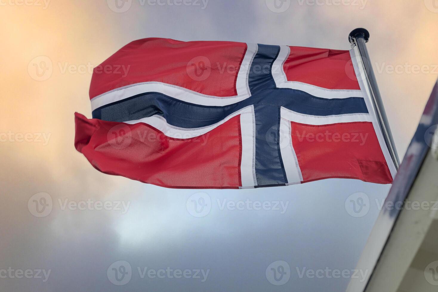 the flag of Norway flutters against the sky photo