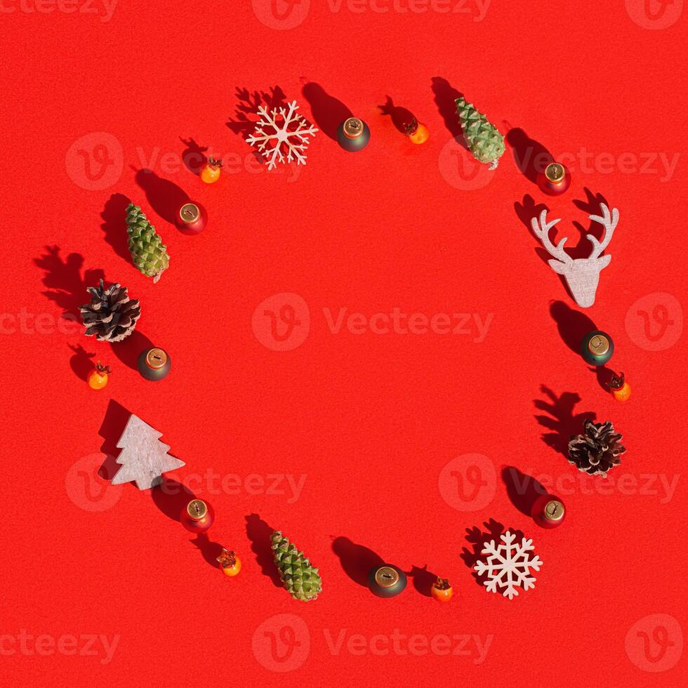 Christmas round frame with natural decorations, wooden toys, pine cone on red Winter celebration concept. photo
