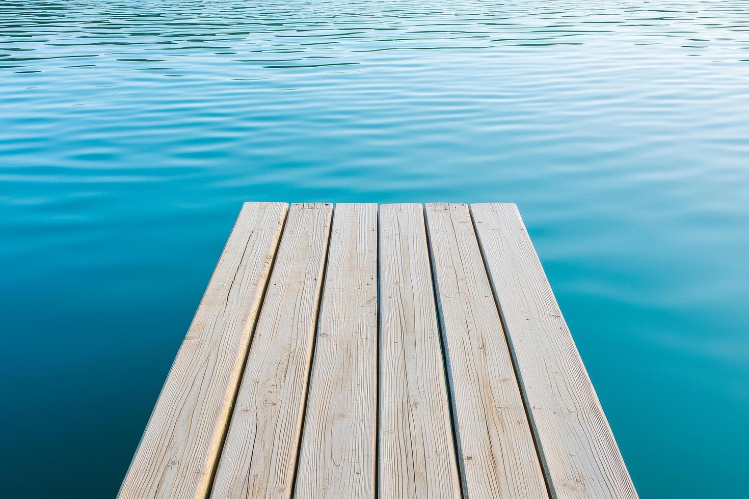 Wooden dock extending over tranquil blue water surface. photo