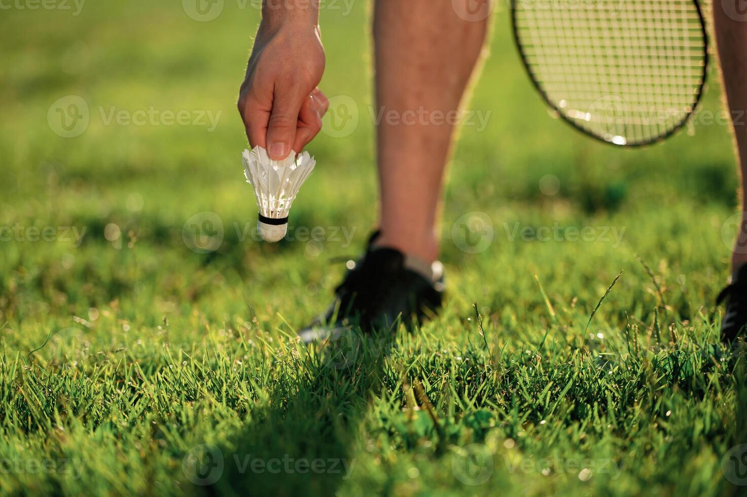 Close, up view of man that is taking shuttlecock from the ground photo
