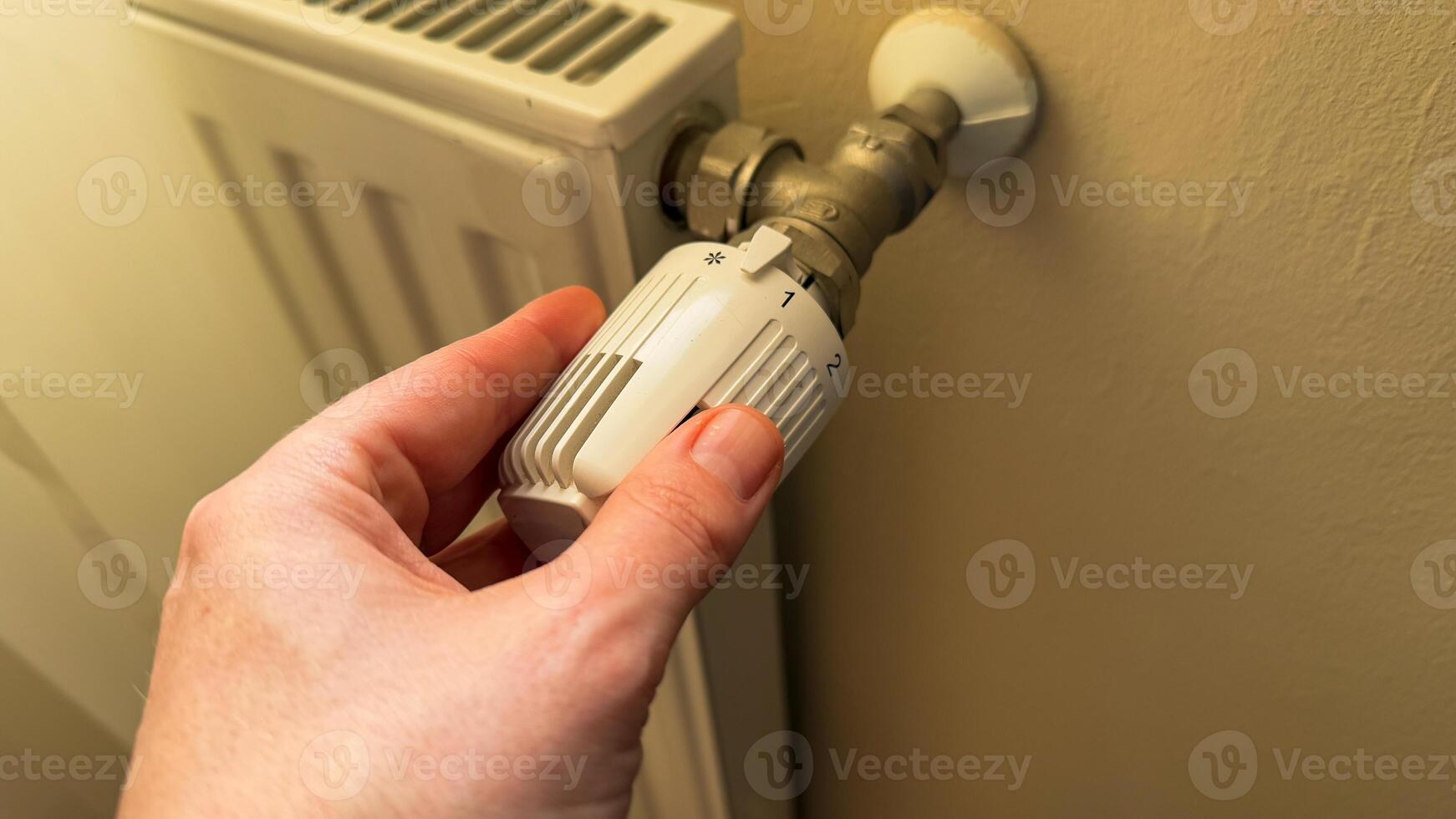 Hand adjusting vintage radiator valve, evoking cozy autumn hygge, energy saving awareness during National Radiator Day, comforting warmth festivity photo