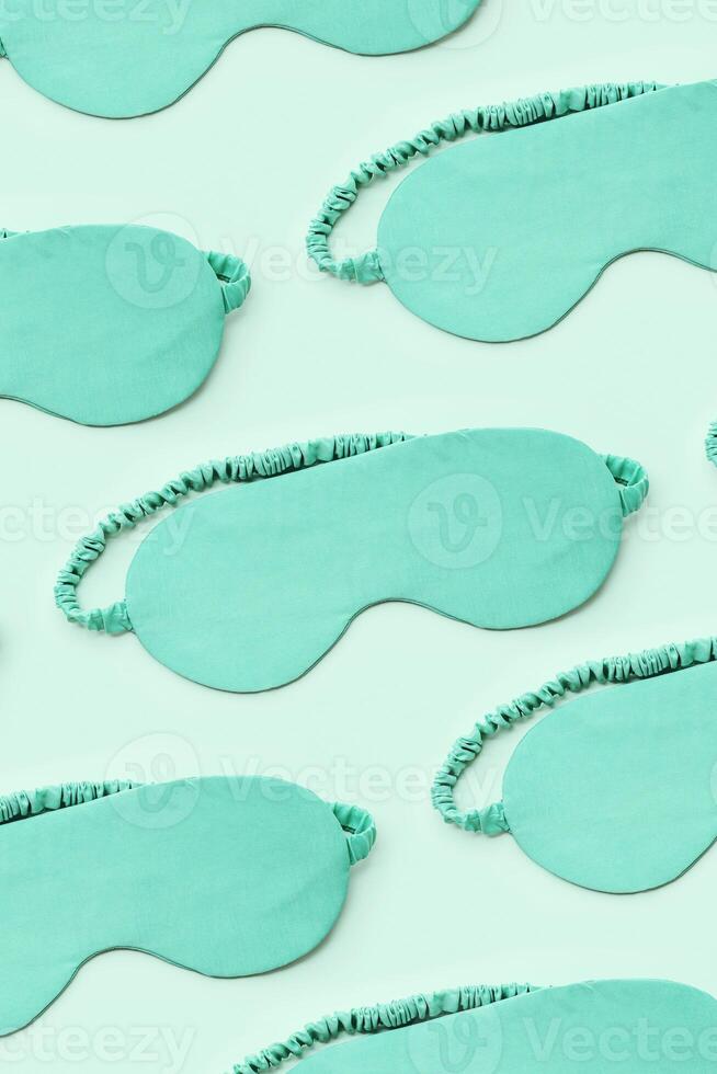 Minimal pattern from silk sleep masks. Turquoise colored eye masks for best sleepers, for travel, comfort rest. Sleep well concept. Creative aesthetic top view, flat lay monochrome pattern photo