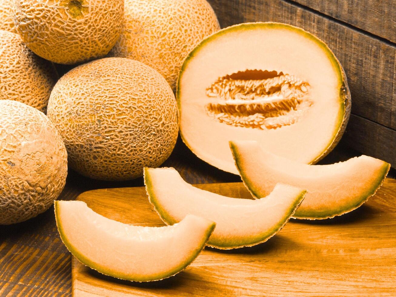 Fresh Ripe Cantaloupe Melon Halves and Slices on Rustic Wooden Background photo