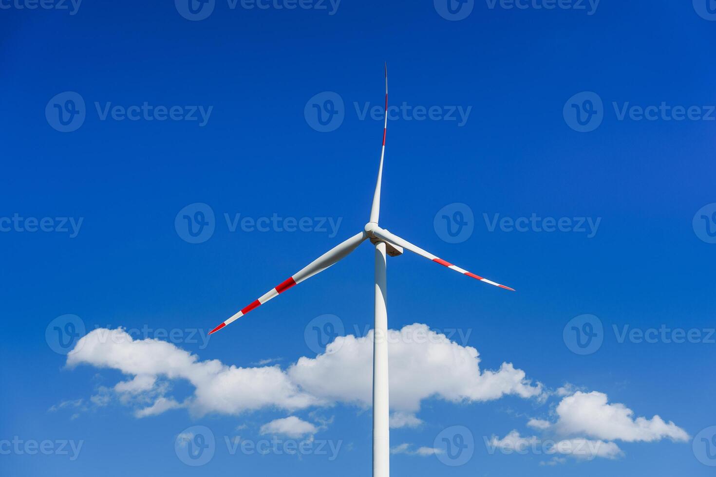 A vibrant image of a wind turbine generating clean energy against a clear blue sky with clouds. Ideal for environmental projects, showcasing sustainable power and a cleaner future. photo