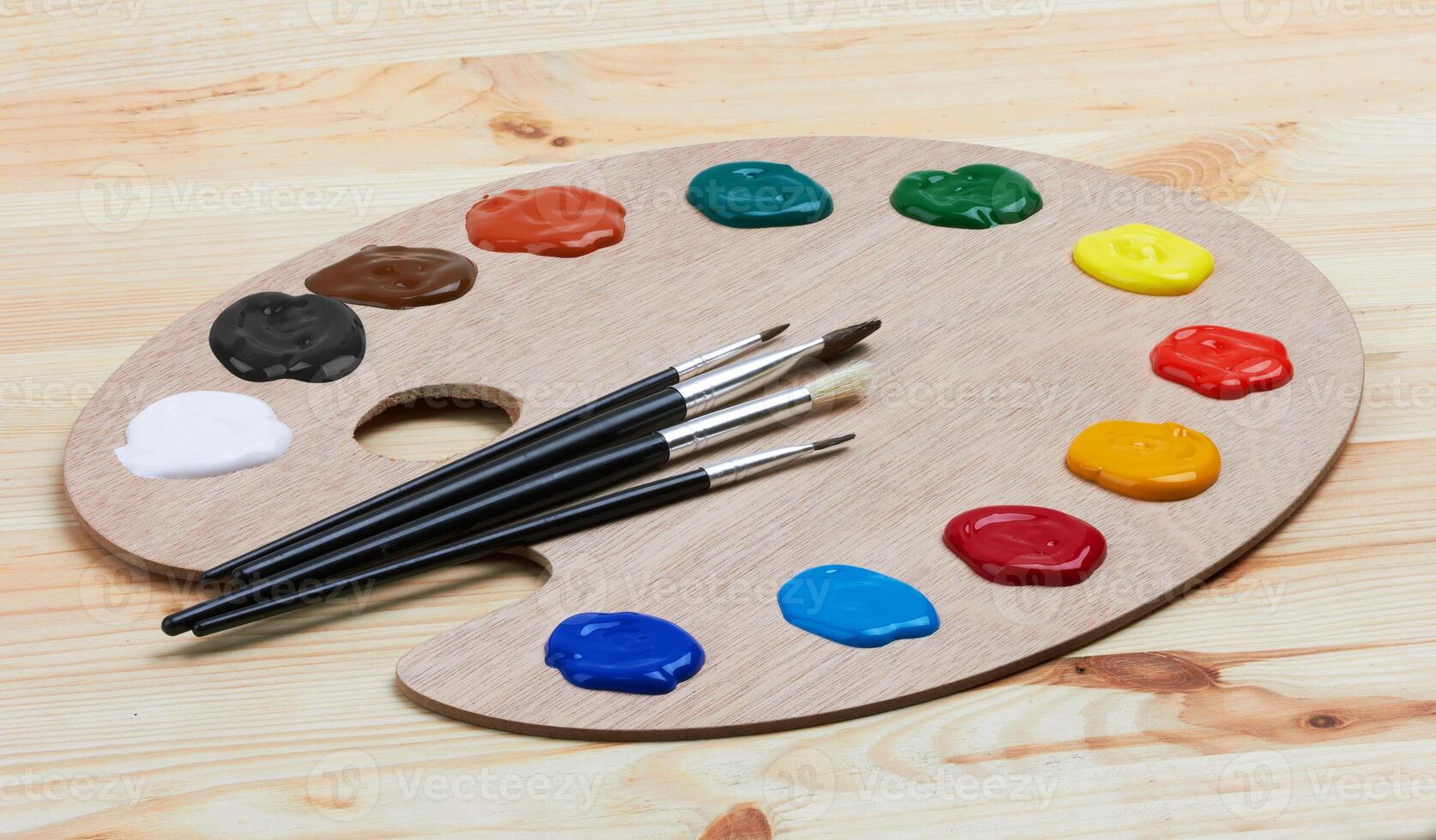Wooden art palette with paint and brushes photo