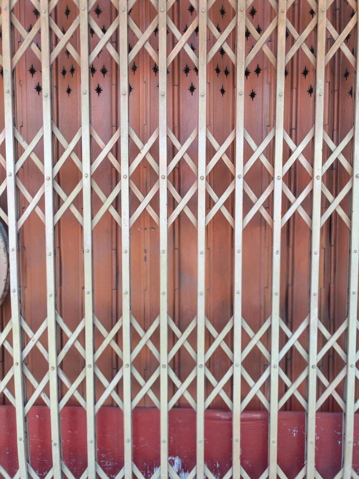 Wooden gate with lattice design and star shaped cutouts at top, set against reddish brown background, creating decorative and functional barrier photo