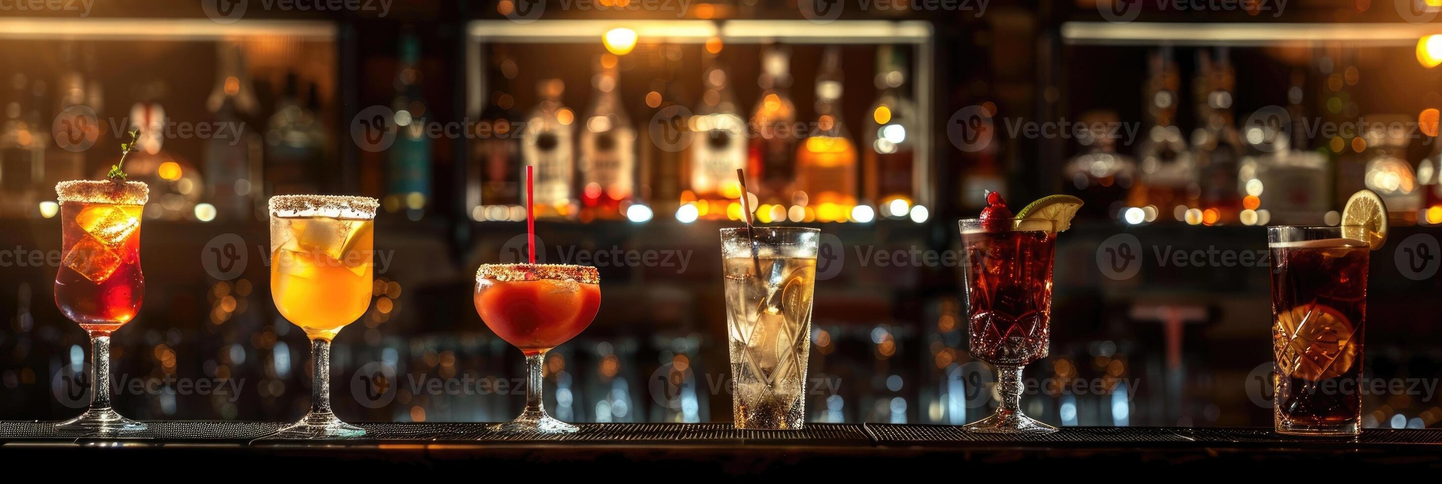 Colorful row of crafted cocktails lined up on bar counter, horizontal banner composition with bottles and bar tools in background photo