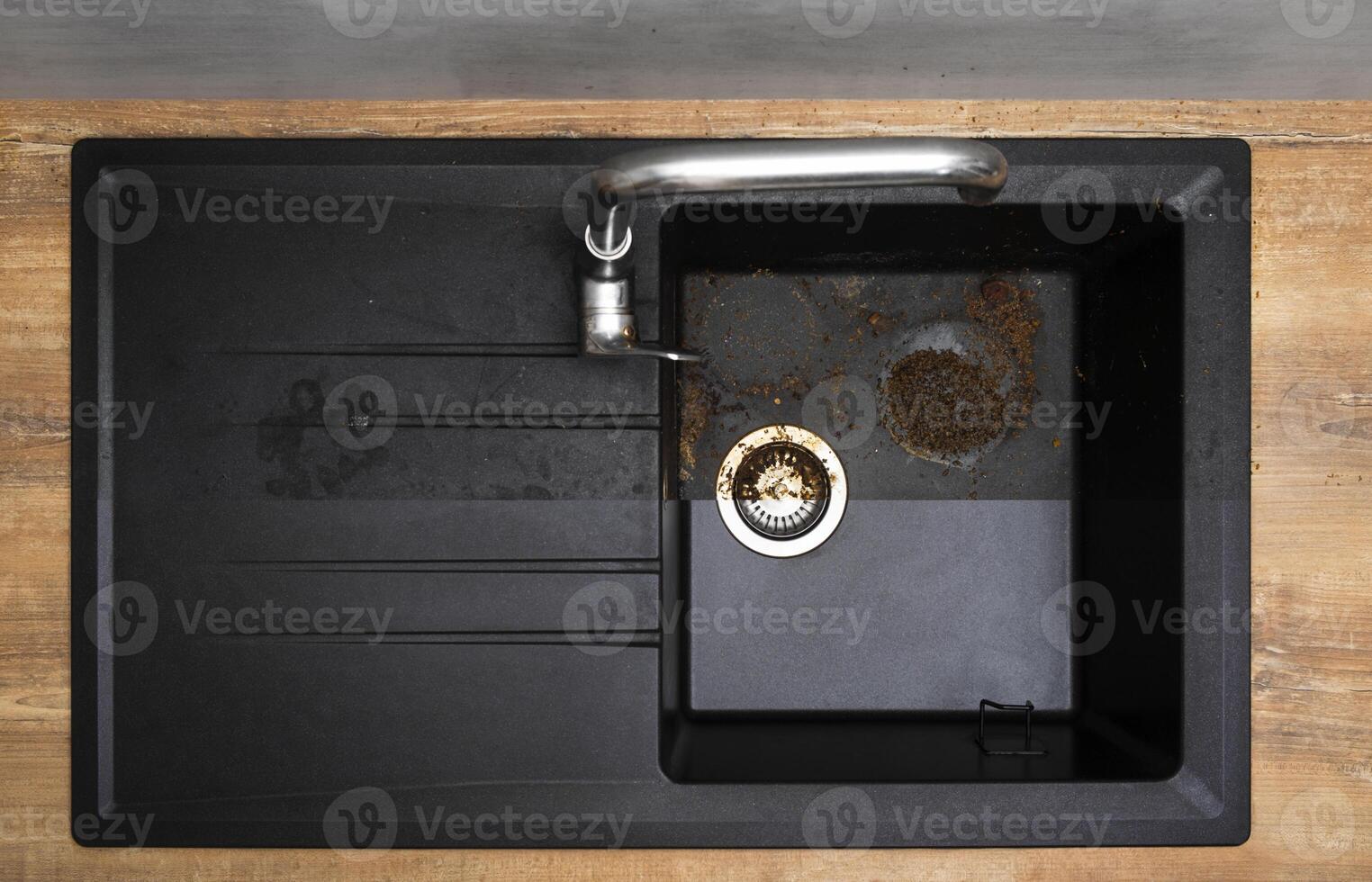 House cleaning service granite kitchen sink black with leftover bits of food before - after washing. photo