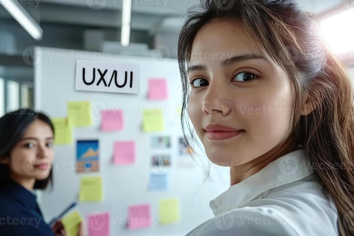 Two women standing in front of a whiteboard with the word uxu on it photo