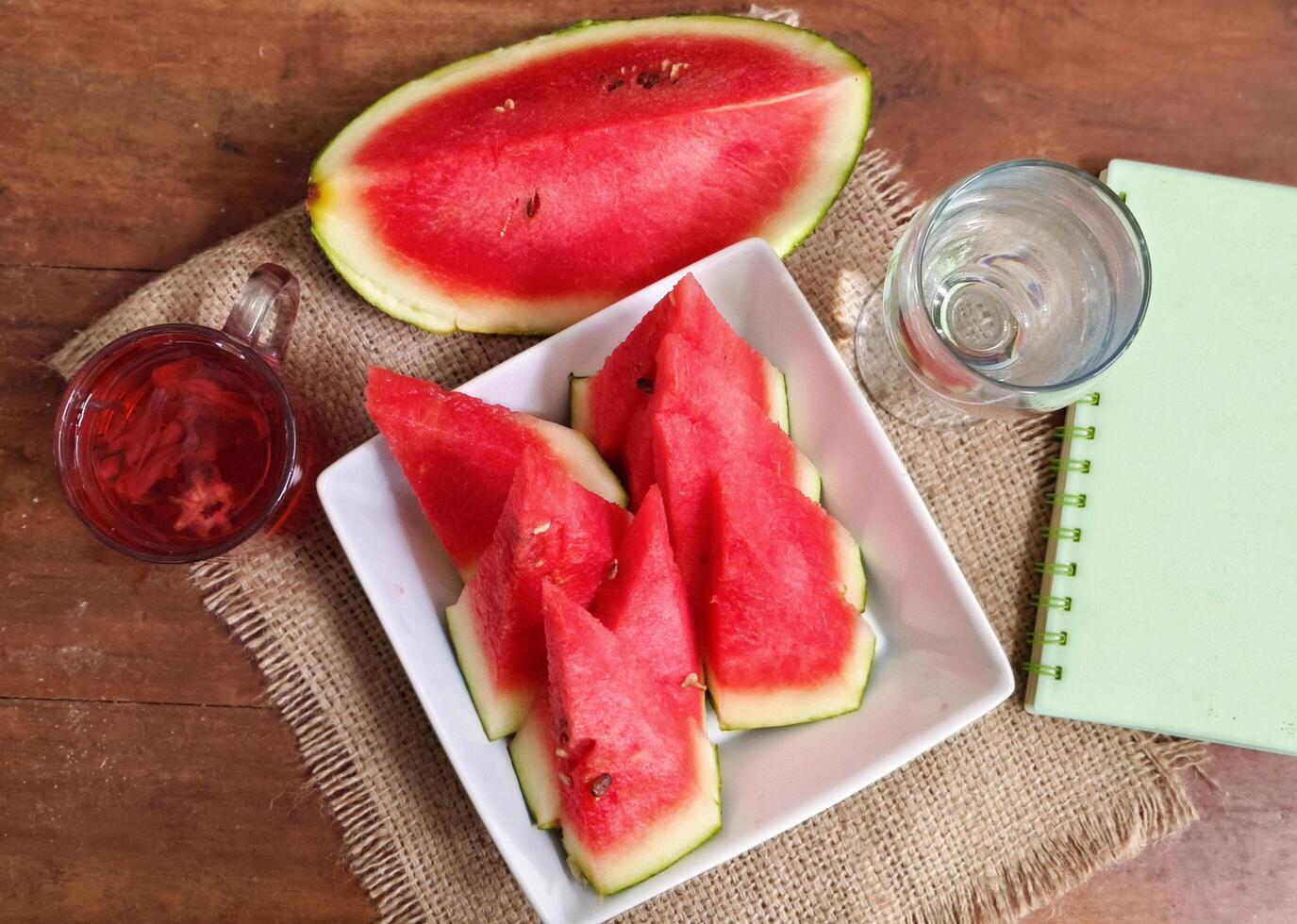 watermelon slices on a white porcelain serving plate and a glass of water and rosella tea for a healthy body photo