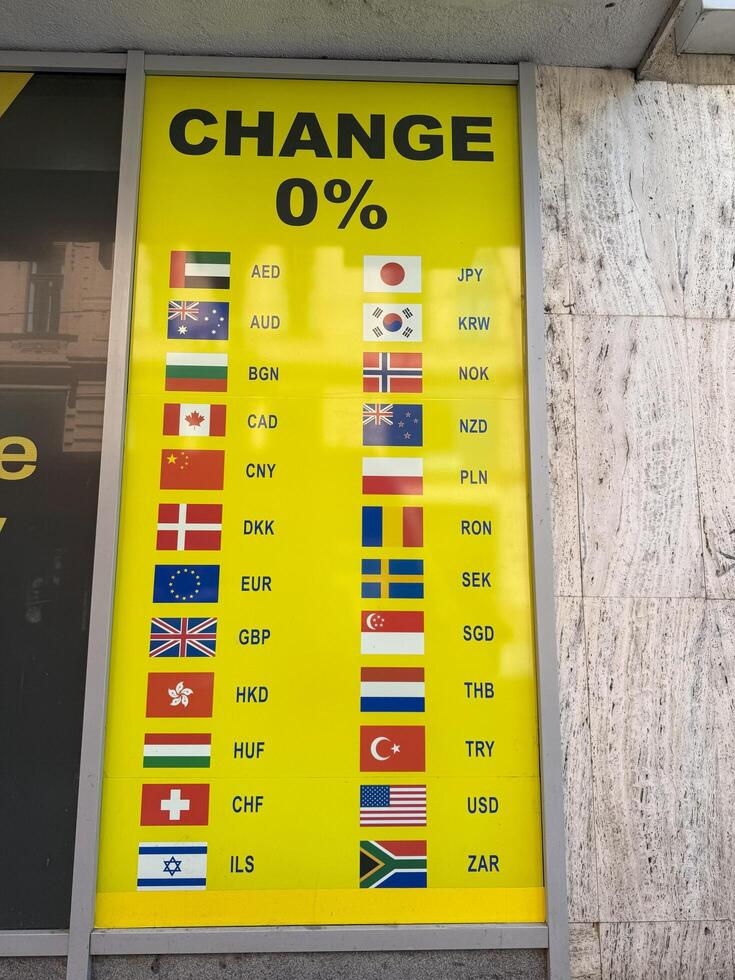 Prague, Czech Republic- June 22,2025.Yellow sign at a currency exchange office displays with various international flags and currency codes for zero percent commission photo