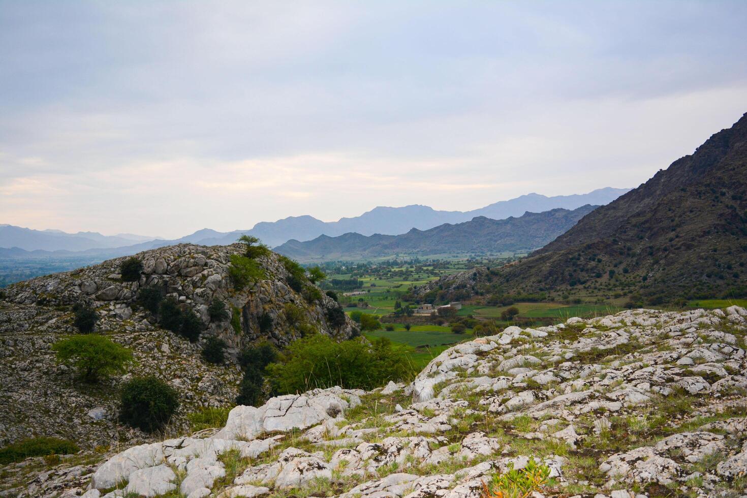 A person is sitting on a rock overlooking a valley photo