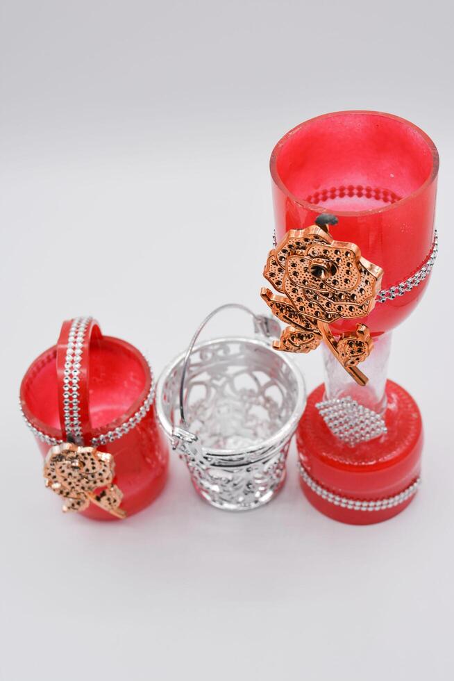 A red glass vase with a silver chain and a silver basket photo