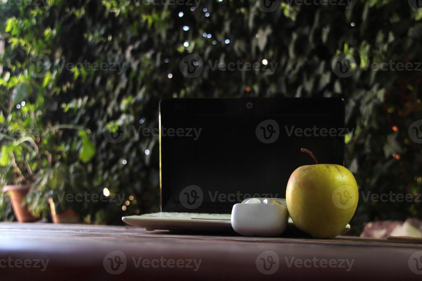 The theme of training, freelancing, education. On the table there is a white laptop and wireless headphones. A green apple indicates a snack photo