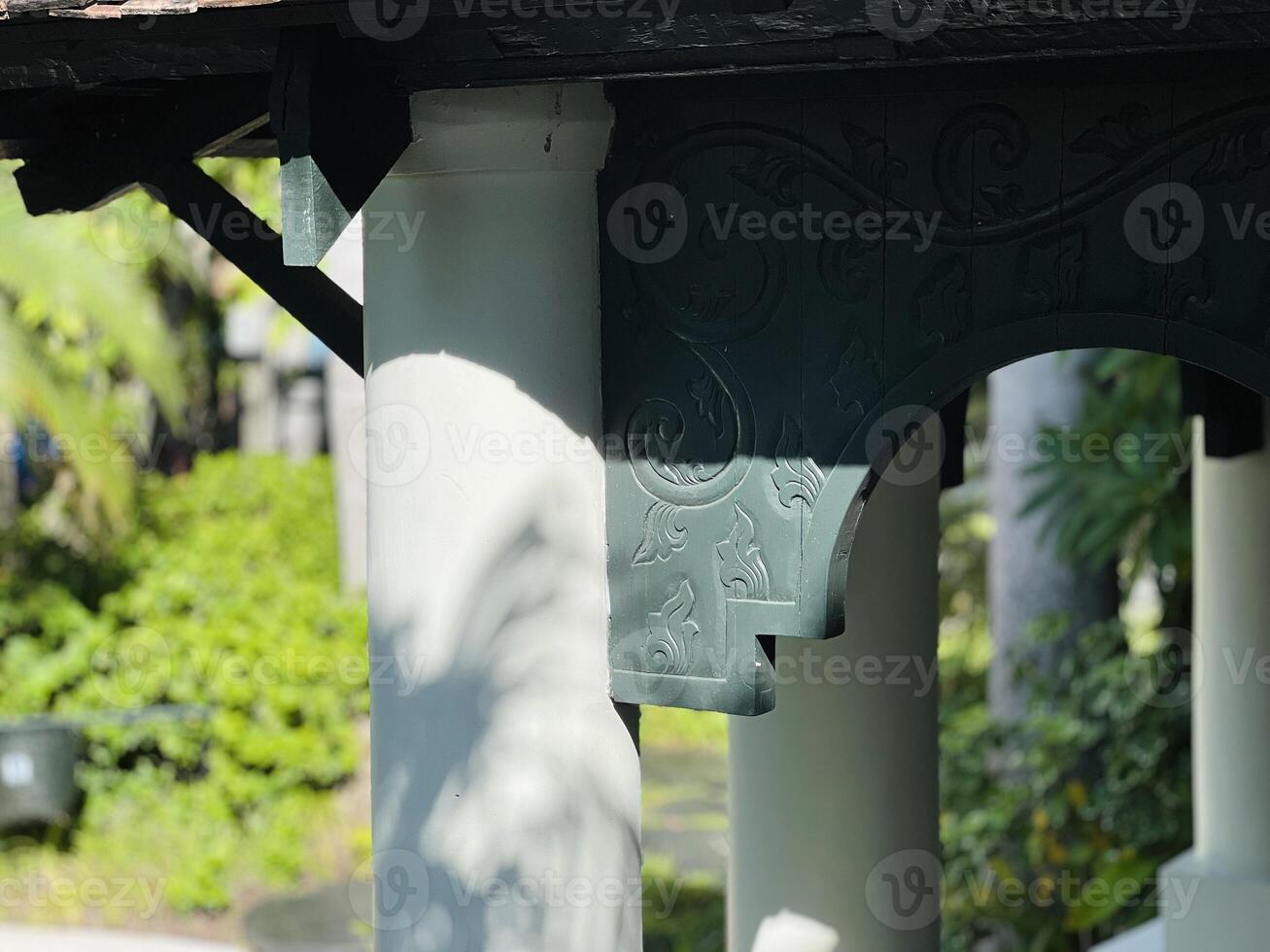 Dark wooden architectural element with ornate floral carvings against a white wall. photo