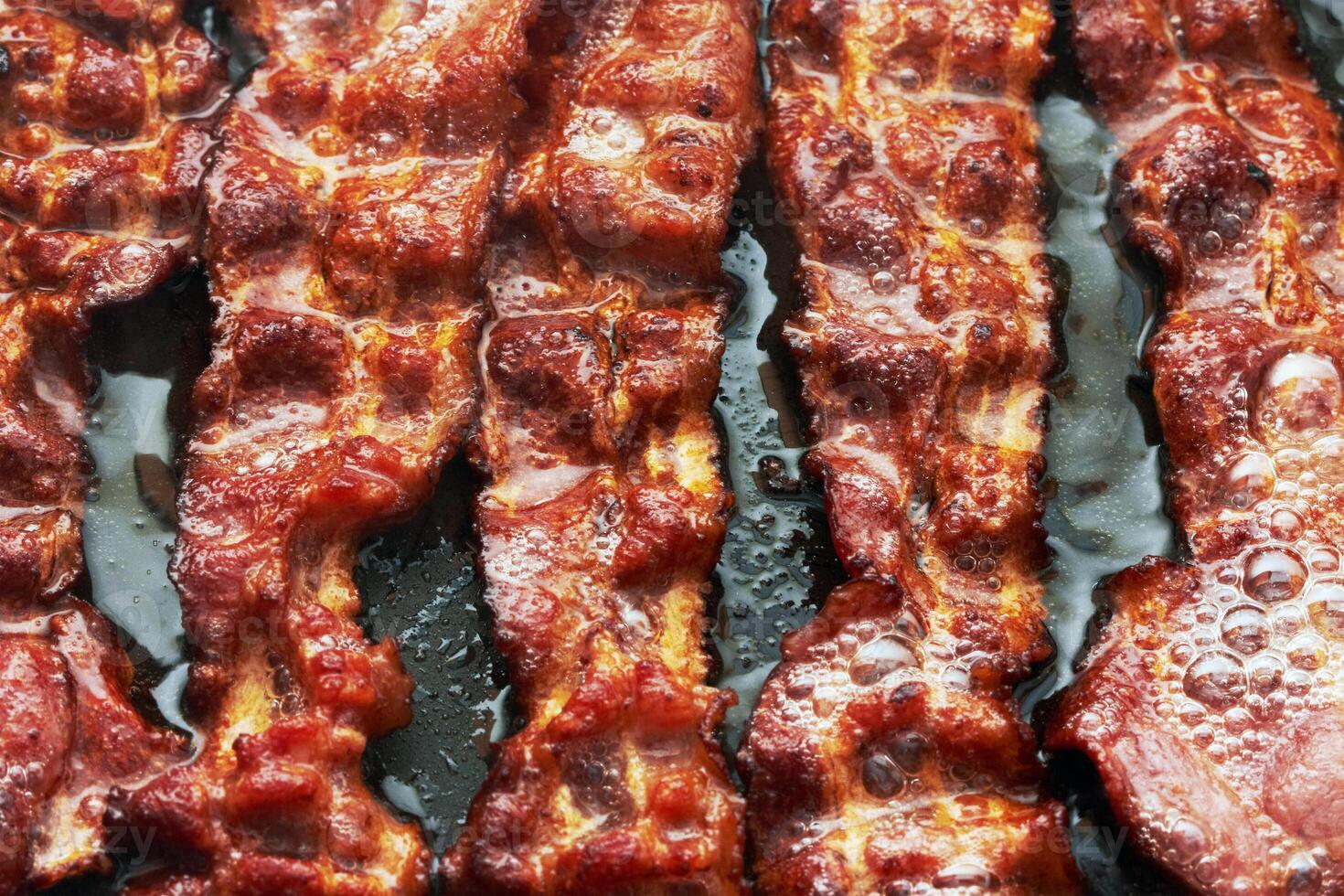 Bacon slice being cooked in frying pan. photo