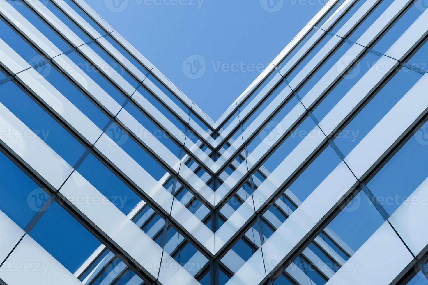 Photo shows a symmetrical view of a modern glass building facade with strong geometric lines. The image highlights architectural design and urban construction for use in business or real estate contexts.