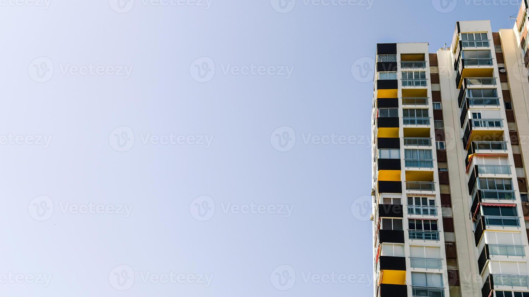 High residential apartments with geometric, colorful balconies under clear blue sky, copy space for text. Urban architecture image for real estate, housing, or city development context photo