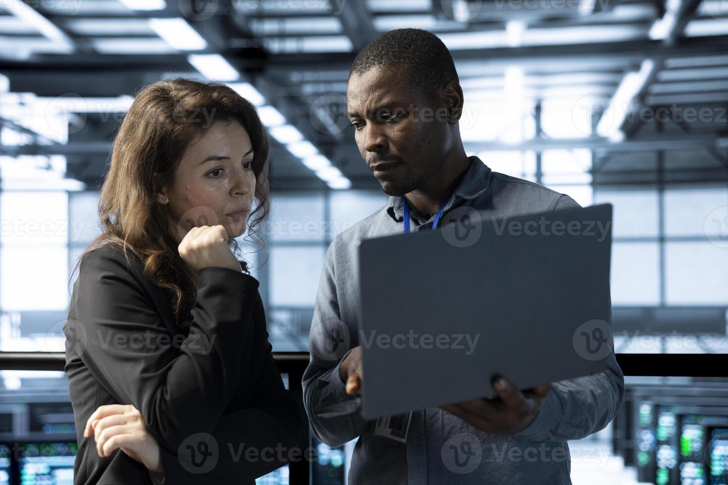 Computer scientists in data center using laptop to develop disaster recovery plans. IT professionals in server farm discussing, testing failover scenarios, protecting data during disruptions photo