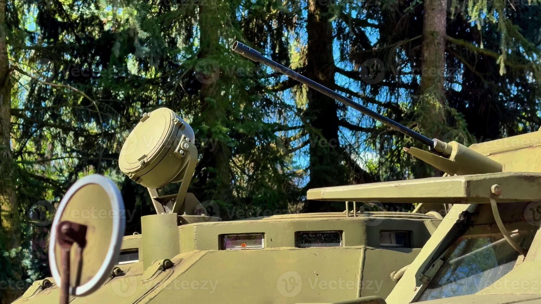A closeup of a military armored vehicle showcases its advanced features, set against lush greenery photo