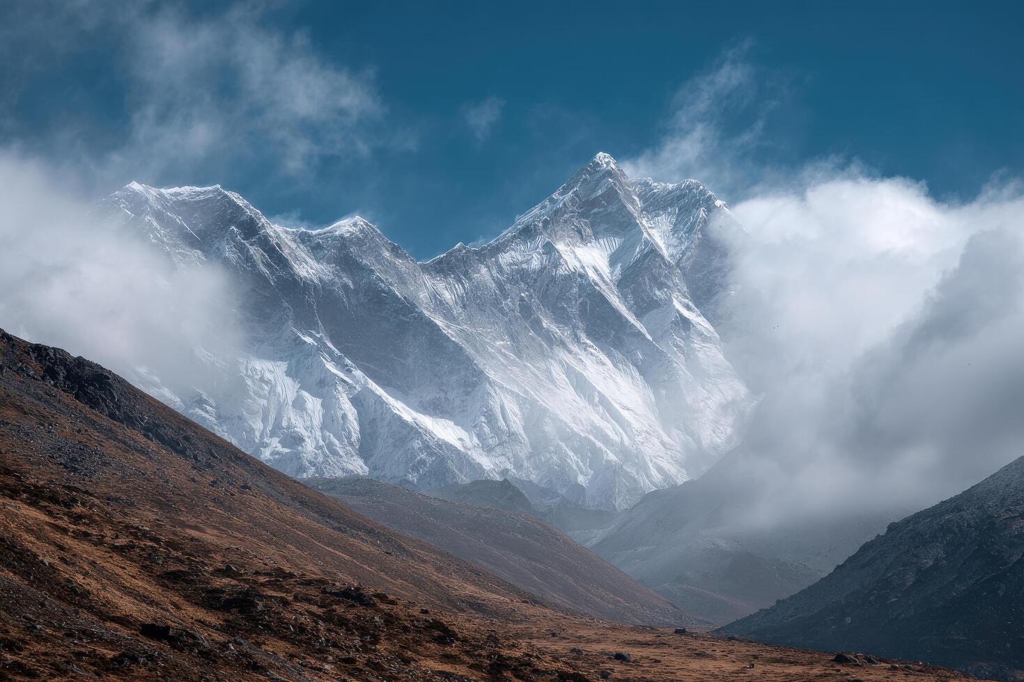 A mountain range with snow capped peaks and clouds photo