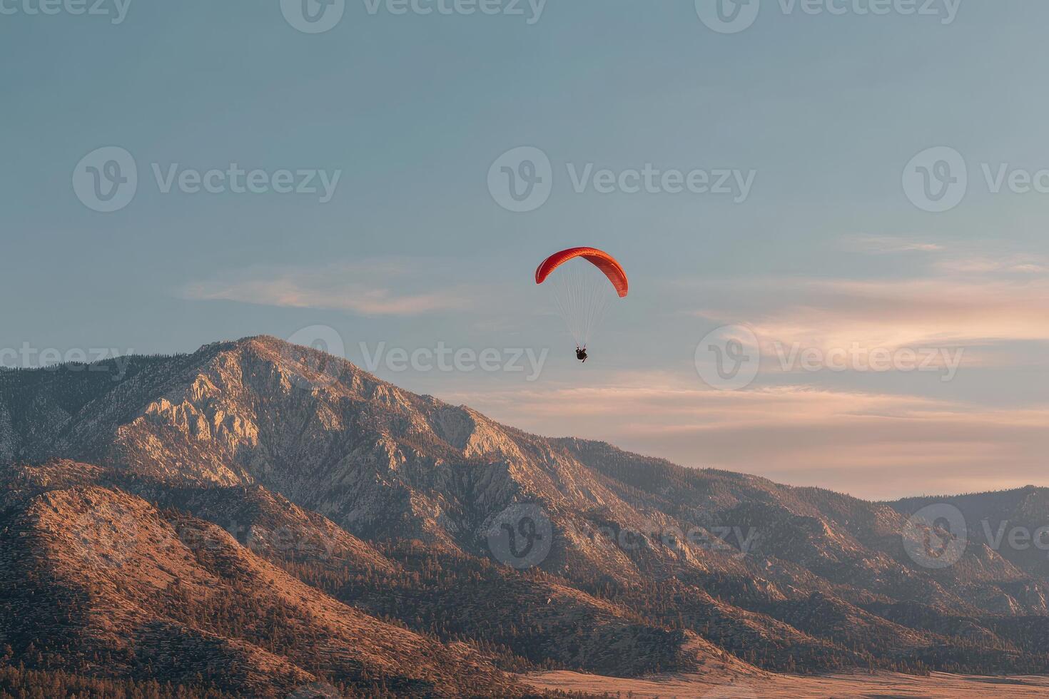 Paraglider flying over mountains at sunset photo
